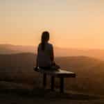 woman sitting on bench over viewing mountain