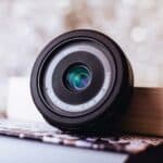 black Canon camera lens leaning on white book