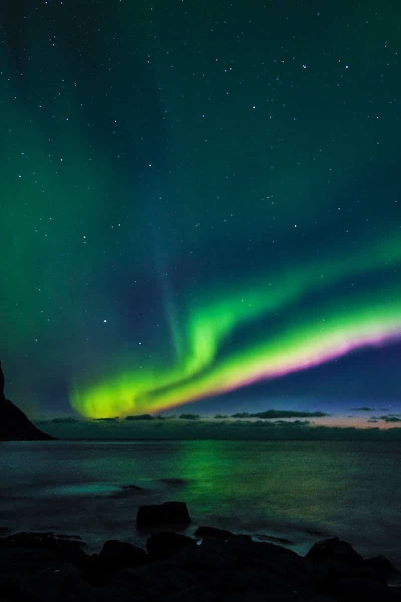 Breathtaking display of Northern Lights over the sea at Myrland, Norway.