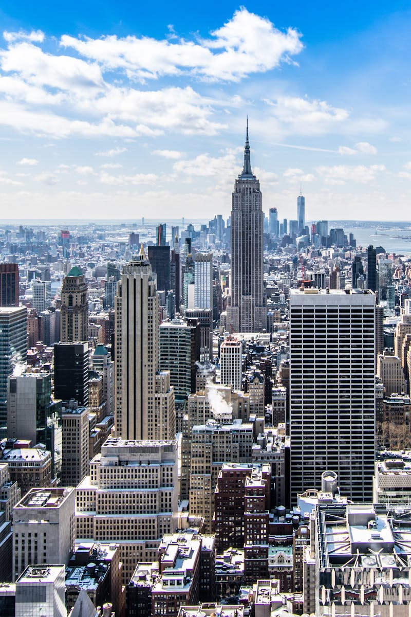 A stunning aerial view of New York City's skyline featuring the iconic Empire State Building under a bright blue sky.